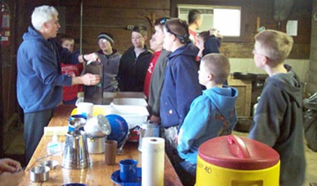 Our Scoutmaster instructing Scouts on the proper care of cast iron cookware, Canyon Camp February 2003.  
Photo by Chris Krumme.
